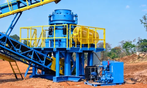 Blue cone crusher installation with yellow access railings, AI-retouched from a licensed site photograph